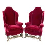 A pair of high wing back armchairs with scroll arms on carved legs and carved front stretchers