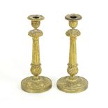 A pair of gilt metal candlesticks, each of column form with foliate decoration on a circular foot,