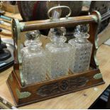 A carved oak tantalus fitted three cut glass decanters (lacking key)