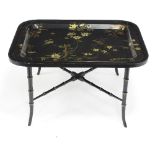 A japanned lacquered tray with gilt floral detailing to a later stand, overall width 83.