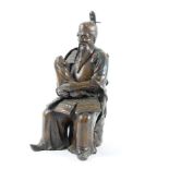 A Japanese bronzed metal figure of a samurai, seated holding a baby,