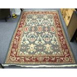 A modern rug with stylised designs on a blue ground within a red border,