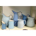 Six blue enamel jugs and two pottery examples