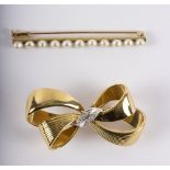 An 18ct gold brooch in the form of a ribbon bow with diamond set white metal detailing to centre