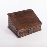 An 18th Century oak Bible box, with sloping fall and carved sides,