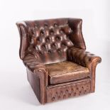 A brown leather button back wing armchair with studded arms Condition Report: Seat