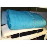 A quantity of various rolls of fabric to include a large roll of blue wool,