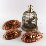 Three ribbed copper blancmange moulds, the largest 34cm and a brass bird cage,