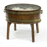 A George III oval wine cooler, brass bound on moulded square legs,