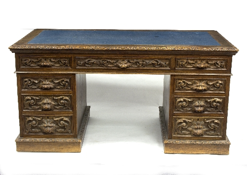 A carved oak pedestal desk, fitted nine drawers around a kneehole,