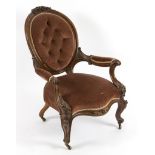 A Victorian walnut framed button back armchair with floral and scroll carving