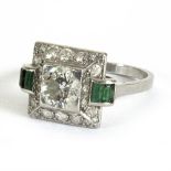 An Art Deco diamond and emerald ring centred by a round mixed cut diamond of approximately 1ct,