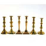 Three baluster brass candlesticks, another and a pair of brass candlesticks with beaded borders,