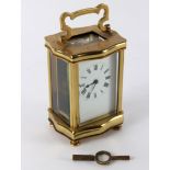 A gilt brass cased carriage clock of serpentine outline, the white enamel dial with Roman numerals,