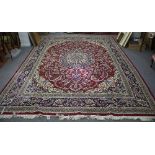 An Eastern style carpet with all over stylised design on a red ground,