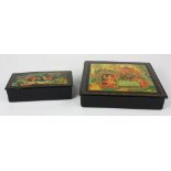 (lot of 2) Russian black lacquer boxes, each lid decorated with traditional folk figural reserves,