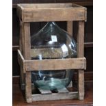 American Primitive style wood crate and glass jug, the jug having a stick neck above the bulbous