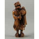 Japanese wood netsuke; oni (demon) in kimono carrying an umbrella on his back and beating a hand