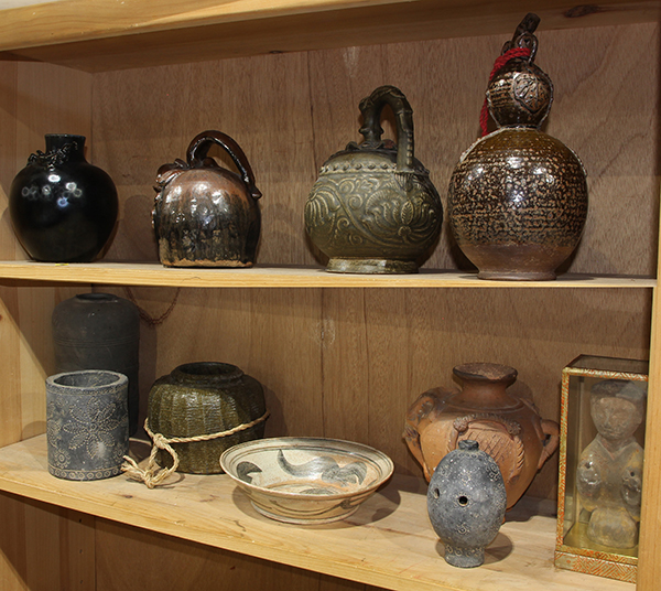 (lot of 11) Two shelves of Asian ceramics, mostly of jars and vases with a dark glaze, a slip