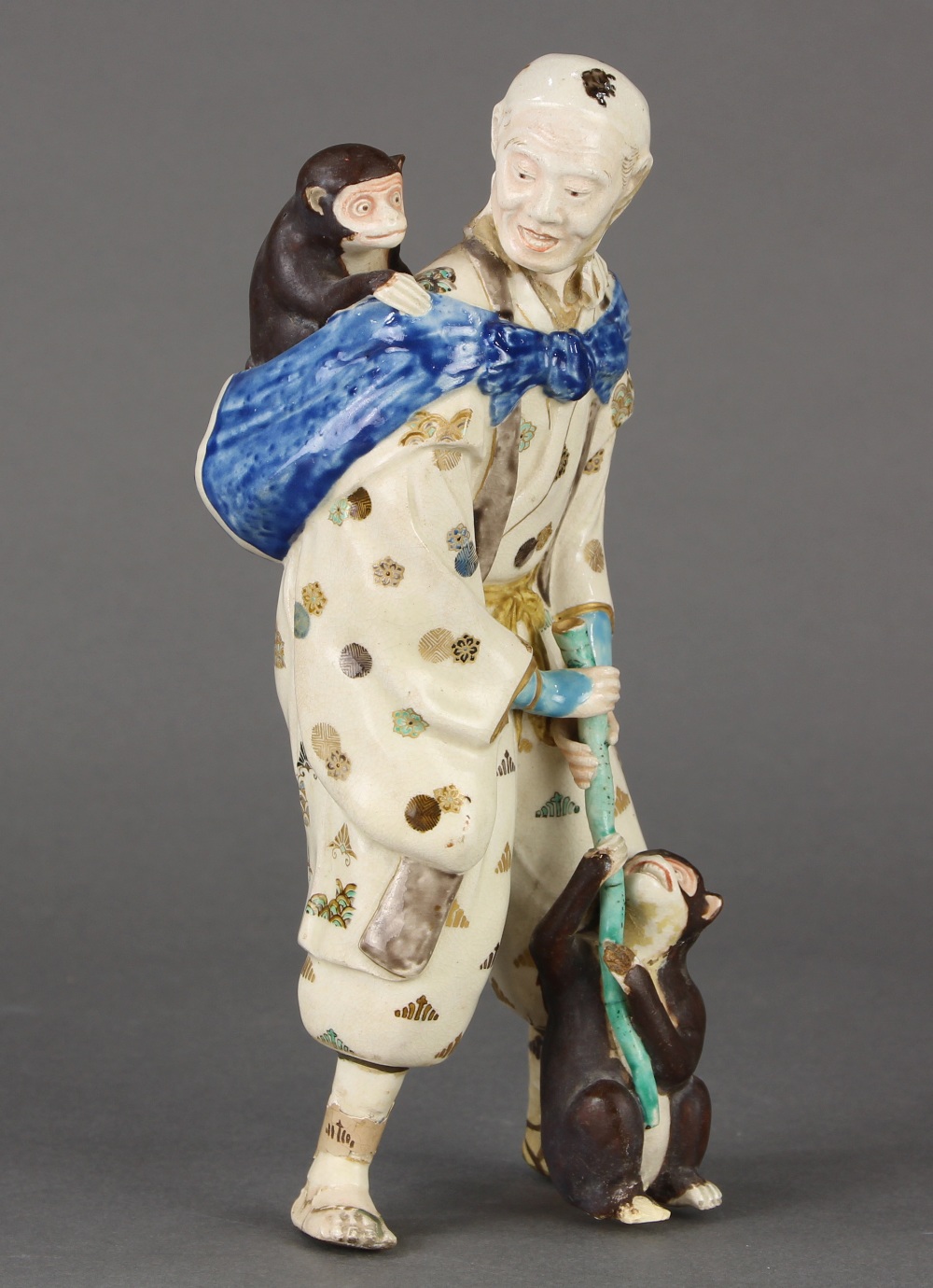 Japanese Satsuma ceramic figure, of a travelling entertainer with a bundle and a monkey on his