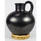 Large Oaxaca blackware water jar, having a single handle above a tapered body resting on a woven