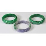 (Lot of 3) Treated jadeite bracelets comprised of one wide treated green jadeite bangle bracelet,