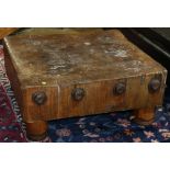 Rustic butcher block, mounted as a low table, having a solid square top, above turned legs, 13.5"h x