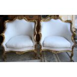 Pair of Louis XV style bergeres, each having a floral carved crest, above a cream upholstered seat