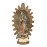 Spanish Colonial Santos figure, 19th century, depicting Madonna surrounded by a gilt ground, above a