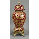 Louis XV style lidded urn, having gilt decoration on a maroon ground, rising on a footed base,