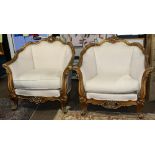 (lot of 2) Louis XV style giltwood bergeres, each having a floral carved crest, above a cream