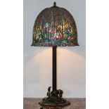 Tiffany style leaded glass table lamp, having a floral decorated domed shade, above a patinated