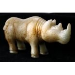 Chinese hardstone carving of a rhinoceros, in formal stance, the off-white matrix with russet