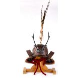 Japanese iron kabuto helmet on a wooden stand, having an iron zoomorphic face with antlers,