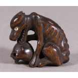 Japanese wooden netsuke, a dog nibbling on a skull, approx. 1.5"l