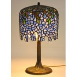 Tiffany style leaded glass "Wisteria" table lamp, having a pierced foral decorated shade, and rising