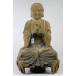 Chinese polychrome wood Buddhist figure, of a seated luohan, with both fists held in front of the