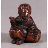 Japanese wooden netsuke, woman holding a pipe, resting on the bundle of brushwood, approx. 1.75"h