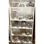 Five shelves of silver plate table articles, including serving trays, lidded tureens, flatware,