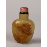 Chinese stone snuff bottle, carved with two fu-lions in relief in contrast with a tan colored