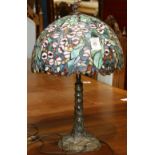 Tiffany style leaded glass table lamp, having a floral decorated multi colored shade and rising on a