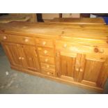 A bespoke made pine dresser base with double cupboard units and 7 drawers