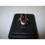 A gold ring marked 585 set with a large central garnet