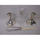 A pair of sterling silver pigmy candlesticks, silver glove stretchers and a silver topped bottle