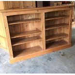 A long low pine bookcase with adjustable shelves