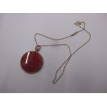 A 9ct gold necklace the pendant set with a red hardstone