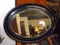 An Oval Antique Mirror With Japanned Frame