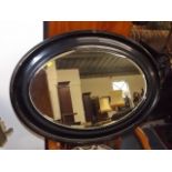 An Oval Antique Mirror With Japanned Frame