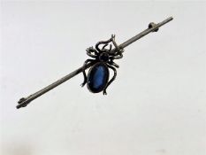 A white metal brooch with blue stone spider
