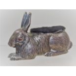 An Edwardian silver pin cushion rabbit with red cabochon stone set eyes, probably ruby